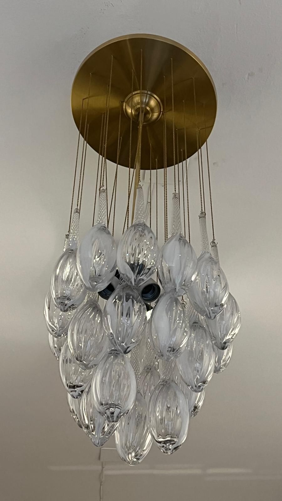 Lámpara de techo dorada con numerosos colgantes de cristal transparente en forma de lágrima.