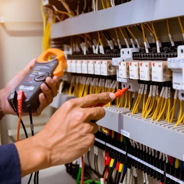 Un hombre está trabajando en un panel eléctrico con un multímetro.
