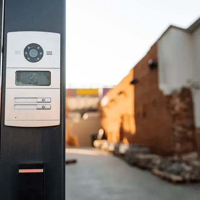 Un primer plano de un timbre en un poste con un edificio de ladrillos al fondo.