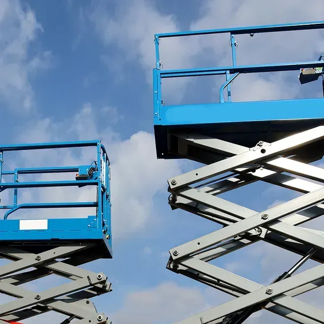 Dos elevadores de tijera azules contra un cielo azul