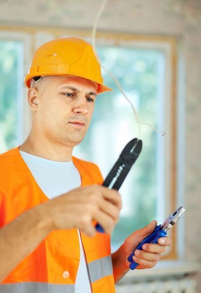 Un hombre con casco sostiene un par de alicates.