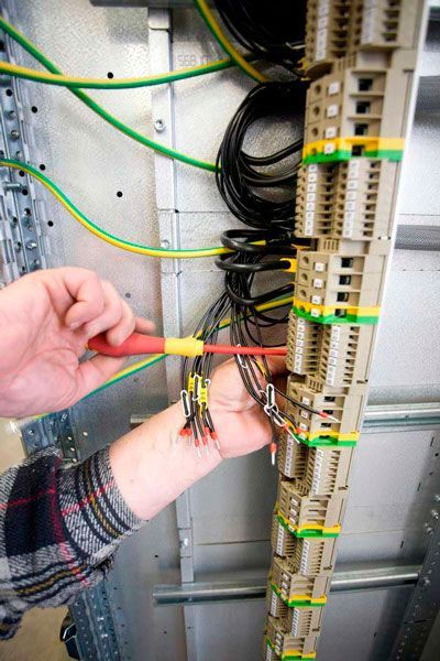 Un hombre está trabajando en un panel eléctrico con un destornillador.