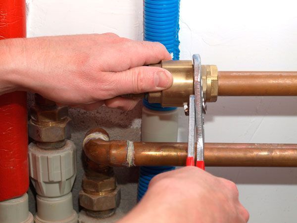 Una persona está arreglando una tubería con una llave inglesa.
