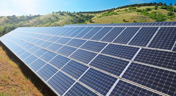 Una fila de paneles solares en un campo con montañas al fondo.