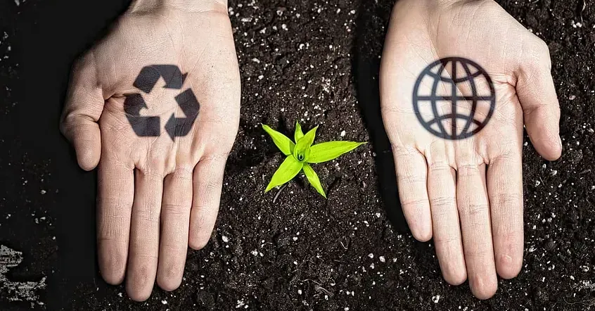 Una persona sostiene un símbolo de reciclaje y un globo terráqueo en sus manos.