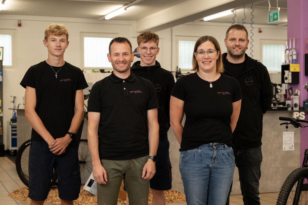 Eine Gruppe von Menschen posiert für ein Foto in einer Fahrradwerkstatt | PS Cycling AG