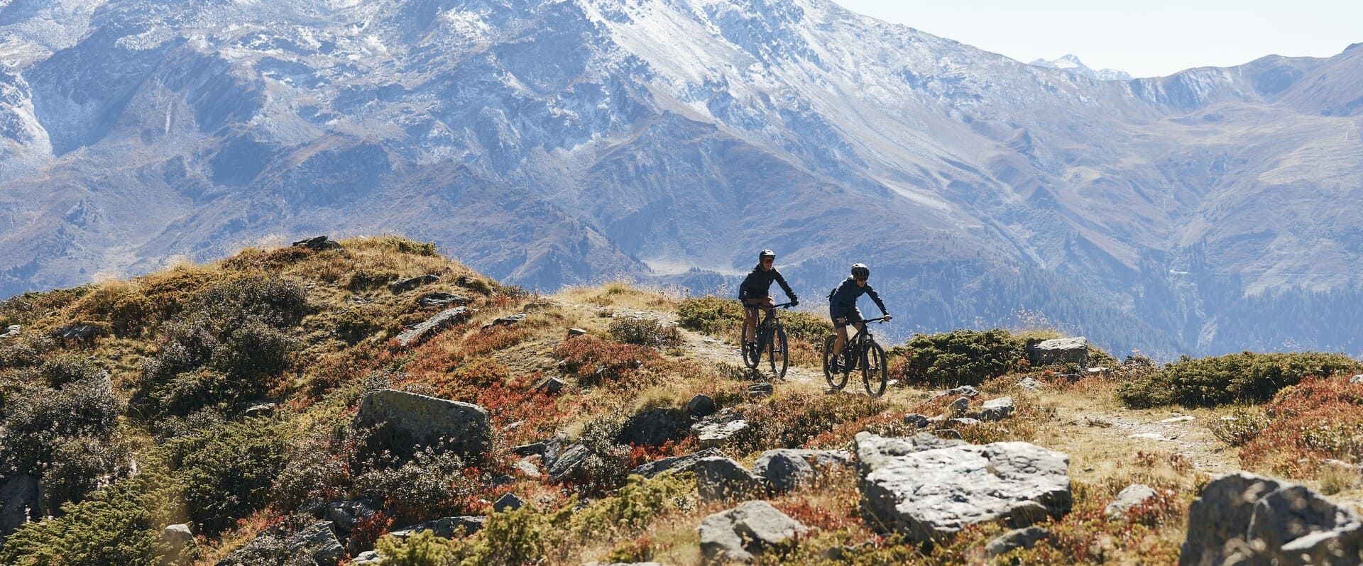 Zwei Personen fahren mit dem Fahrrad auf einem Wanderweg in den Bergen | PS Cycling AG