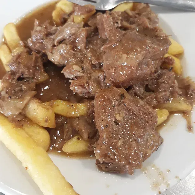 Un primer plano de un plato de comida con papas fritas y salsa.