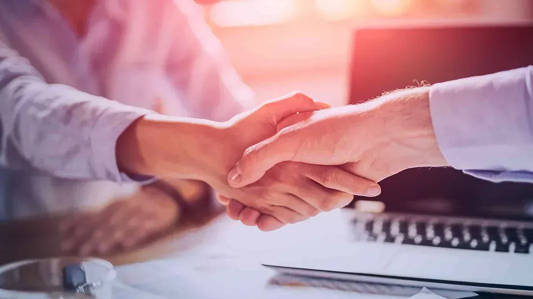 Un hombre y una mujer se dan la mano sobre una mesa.