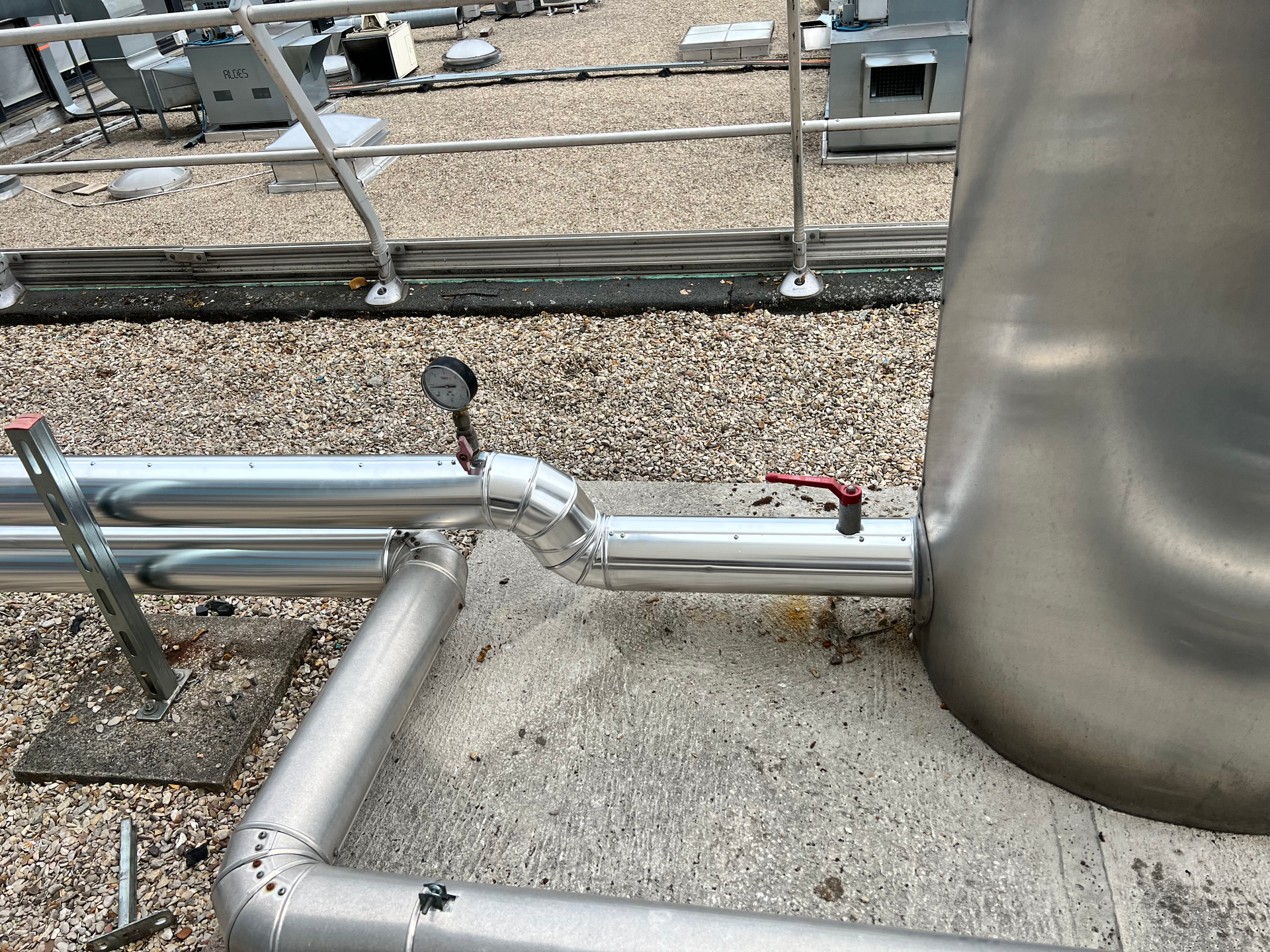 Un gros plan d'un tuyau en acier inoxydable sur un toit en gravier.