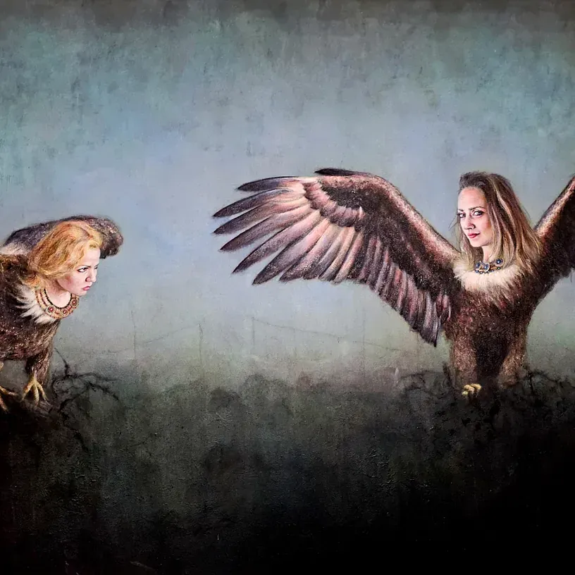 Una mujer está de pie junto a un águila con sus alas abiertas.