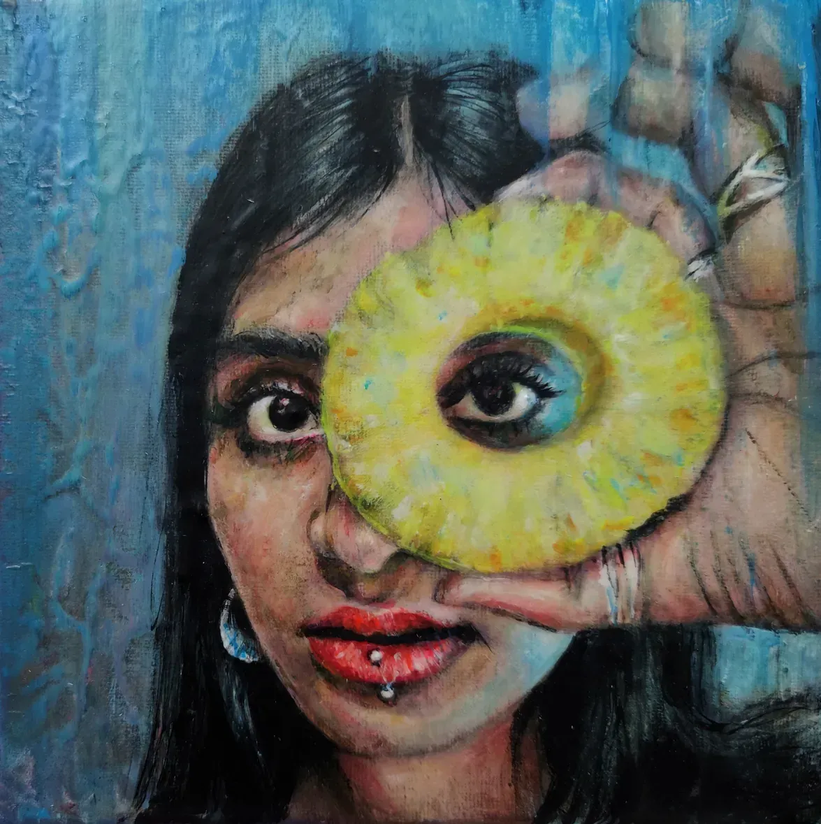 Una mujer sostiene una rodaja de piña delante de su ojo.