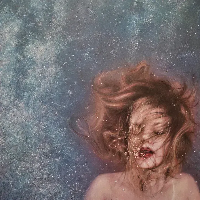 Una mujer está nadando bajo el agua con su cabello ondeando al viento.