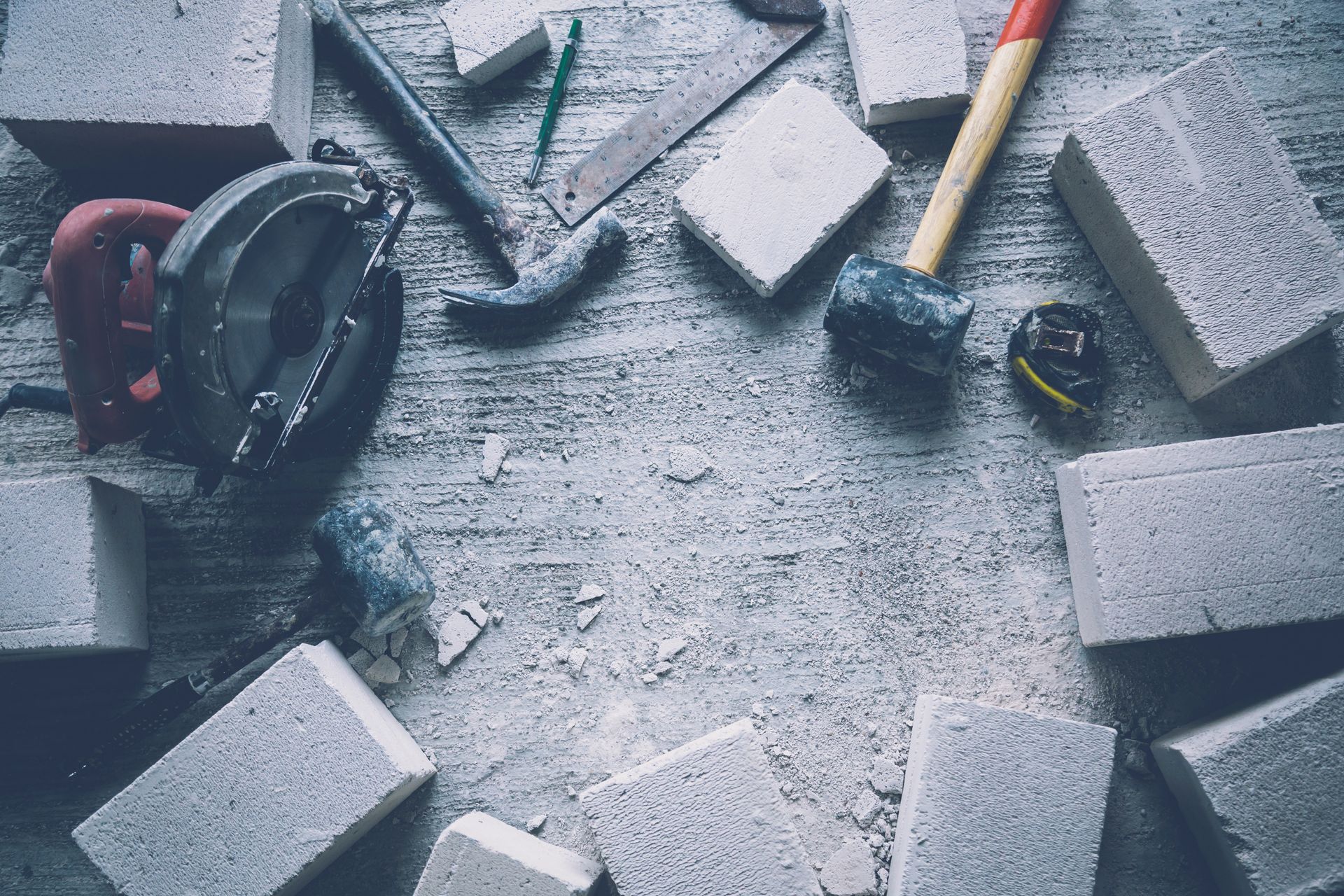Des outils divers et des blocs de mousse éparpillés sur une surface de travail grise, avec un crayon et un pinceau visibles.