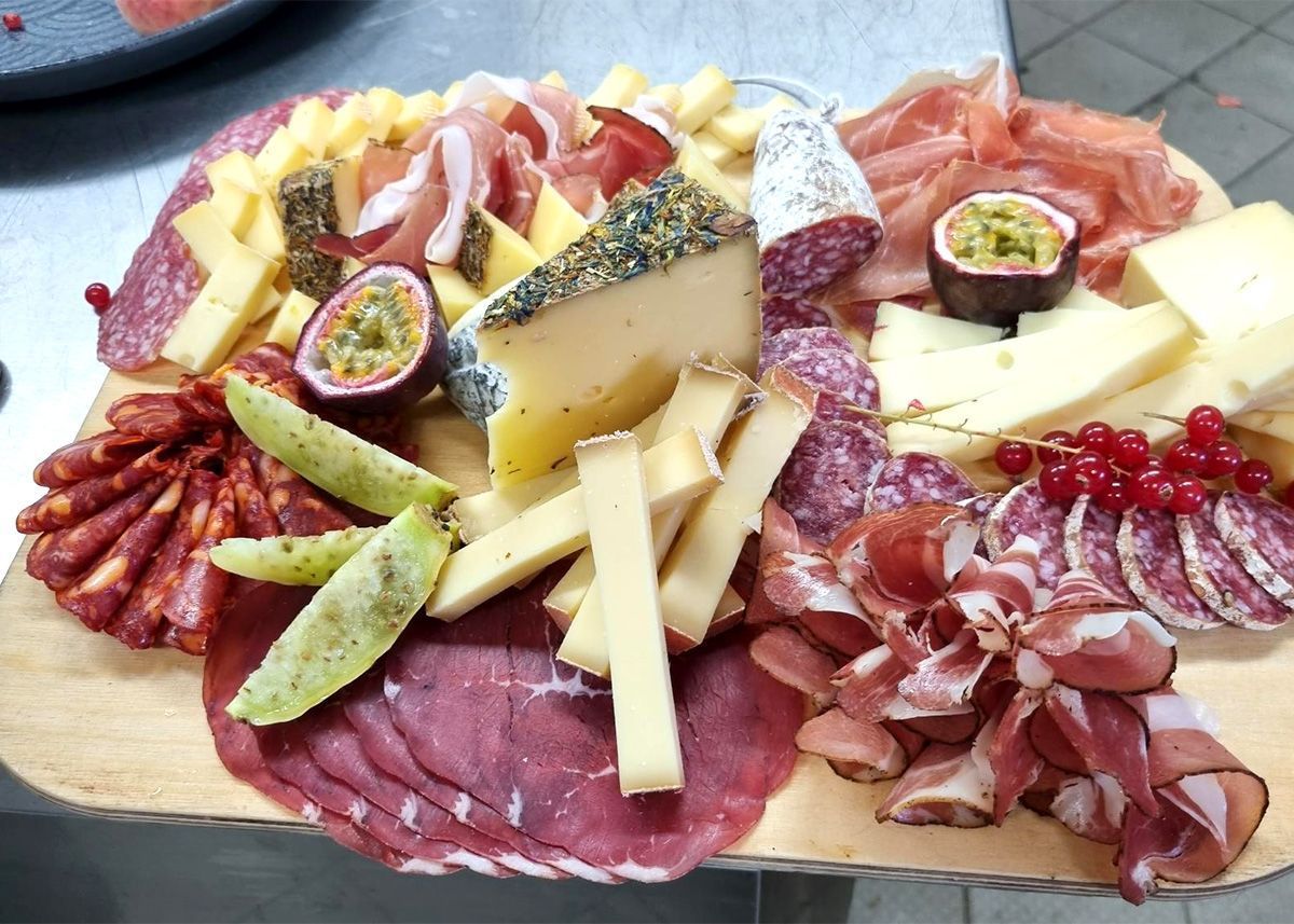Wurstplatte mit Käse, Wurstwaren, Trauben, Feigen, Crackern und Trockenfrüchten auf einem Holzbrett