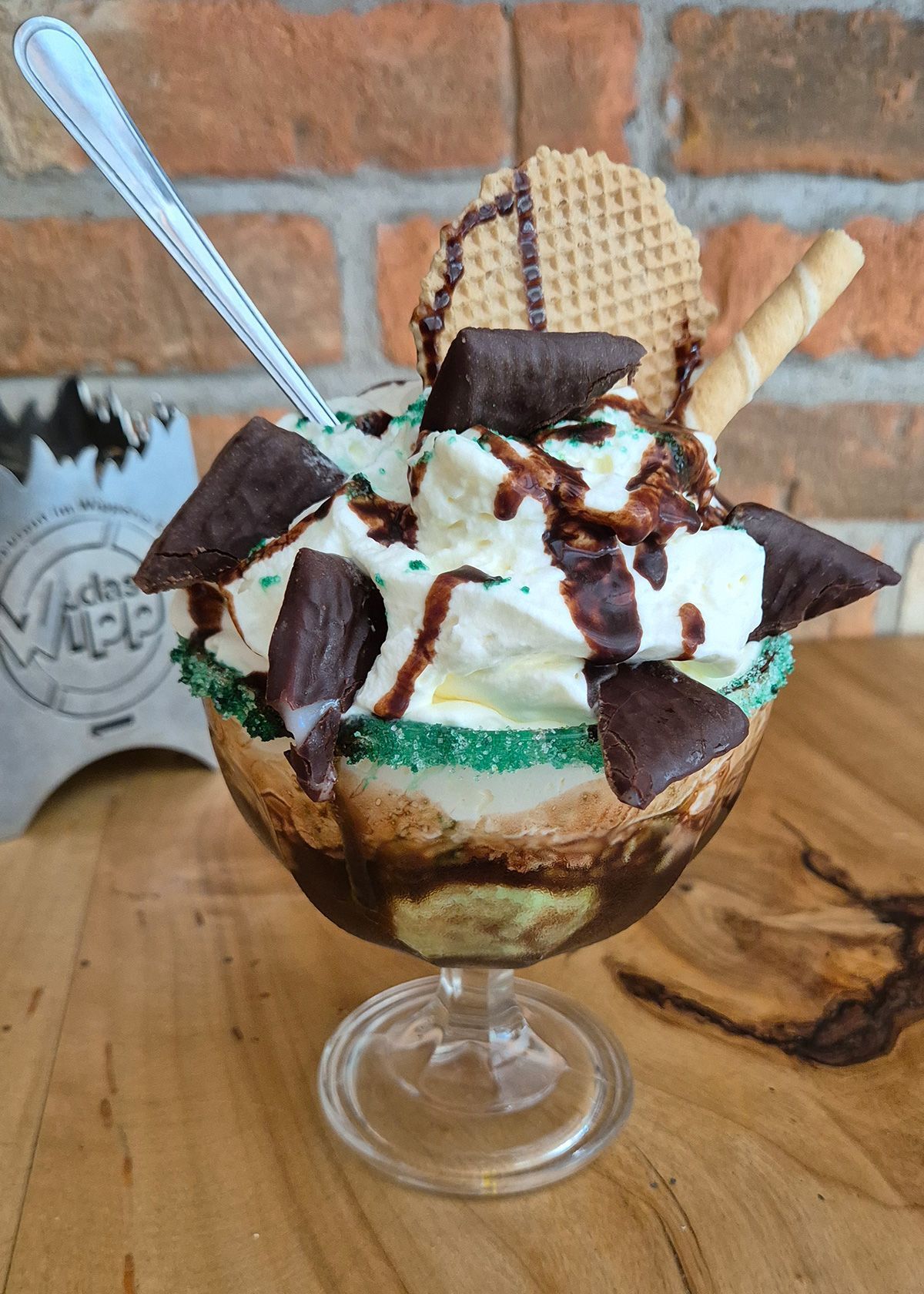 Schokoladen- und Sahneeisbecher in einer Glasschale mit Waffel und Löffeln auf einem Holztisch