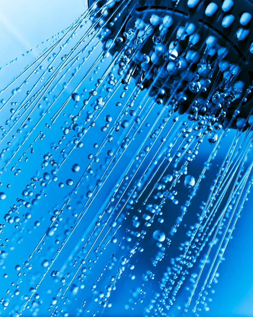 Gros plan sur un pommeau de douche avec des gouttelettes d'eau ruisselant vers le bas, sur fond bleu.