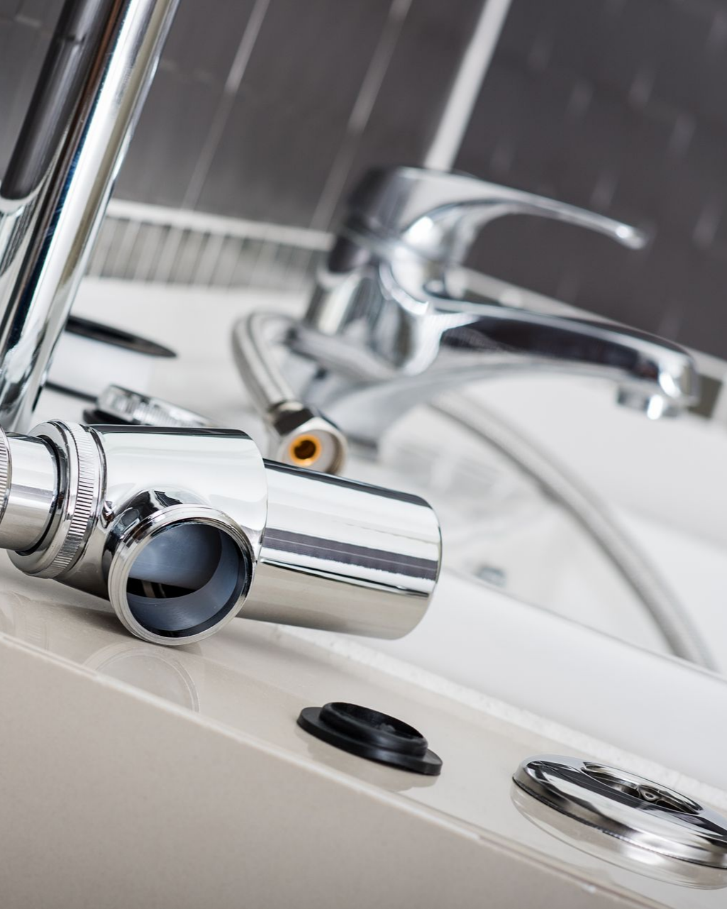 Robinetterie chromée démontée sur un plan de travail blanc.