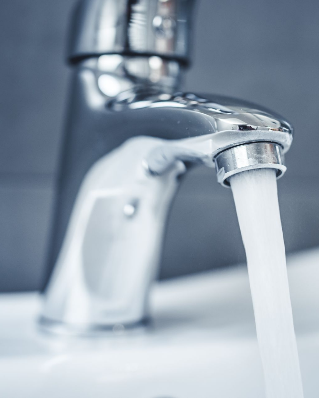 Robinet chromé d'où l'eau s'écoule dans un évier blanc.
