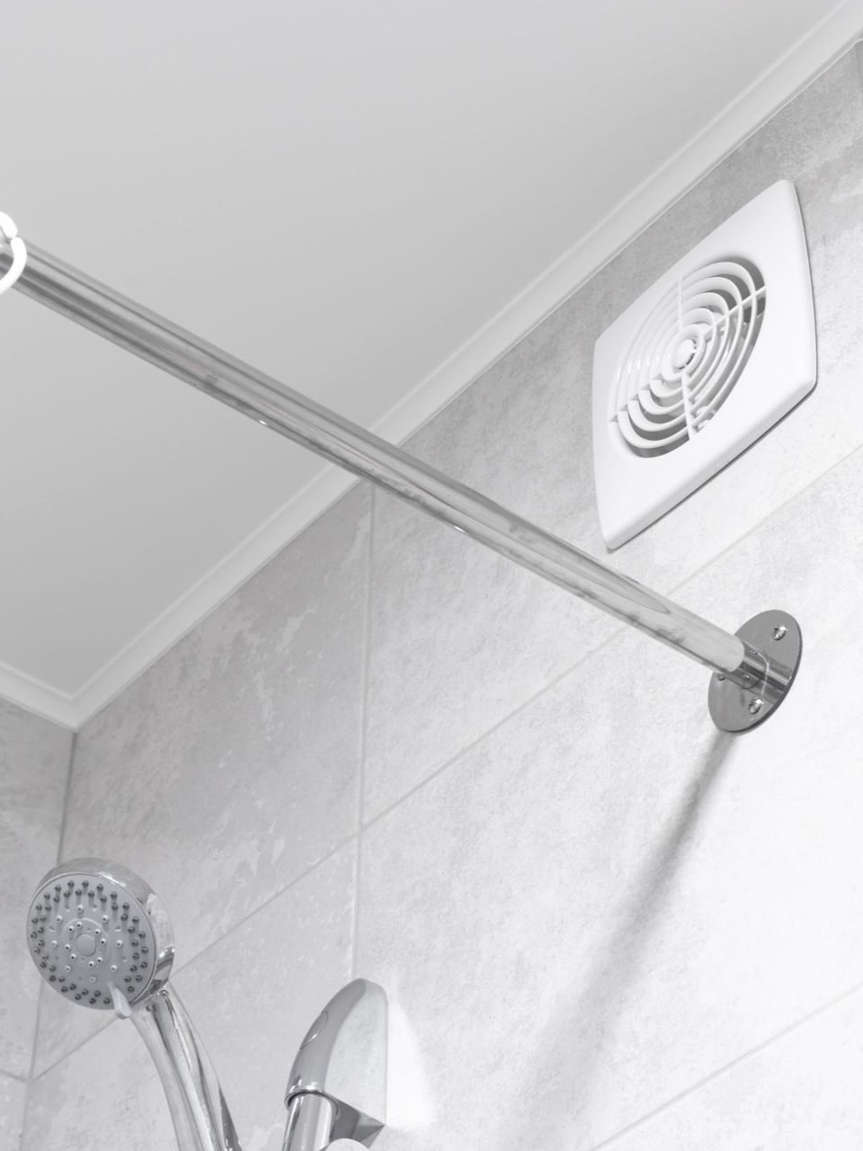 Douche avec barre métallique, pommeau de douche et ventilateur d'aération sur un mur carrelé.