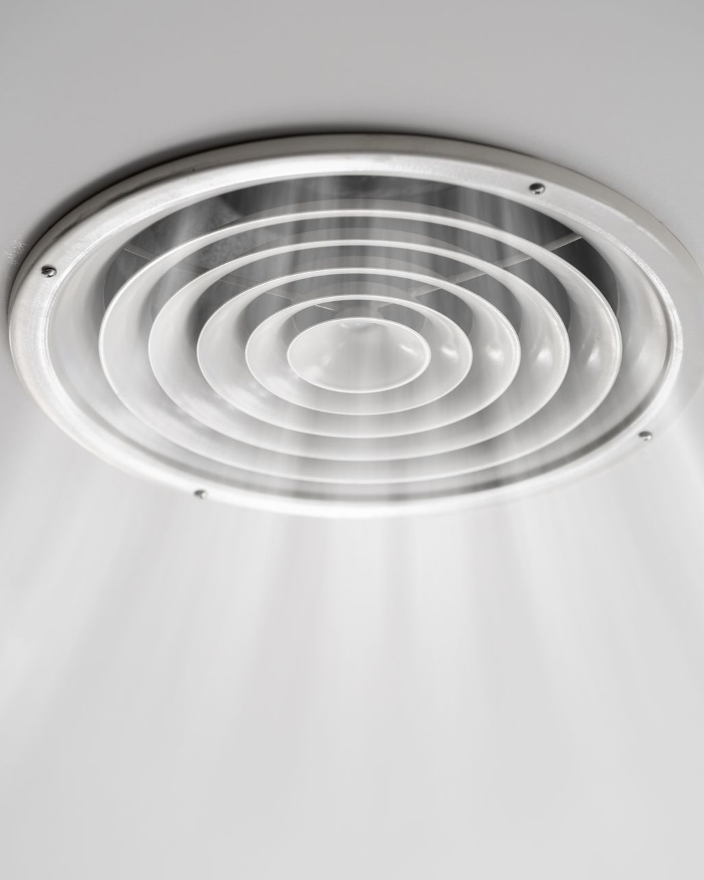 Grille d'aération circulaire de plafond, blanche, à anneaux concentriques.