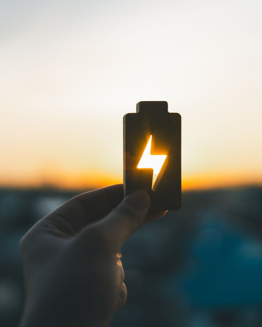 Silhouette d'icône de batterie avec un éclair, rétroéclairée par le soleil couchant.