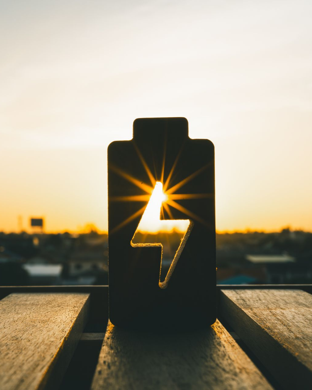 Silhouette d'icône de batterie avec un éclair, rétroéclairée par le soleil couchant.