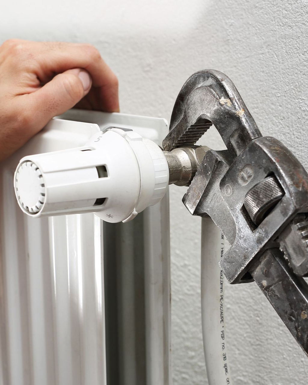 Serrage manuel d'un raccord de tuyau sur un radiateur à l'aide d'une clé réglable.