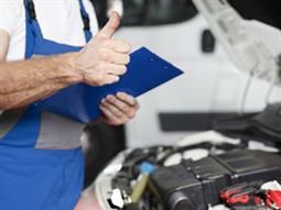 Ein Mechaniker zeigt einen Daumen nach oben und hält ein Klemmbrett.