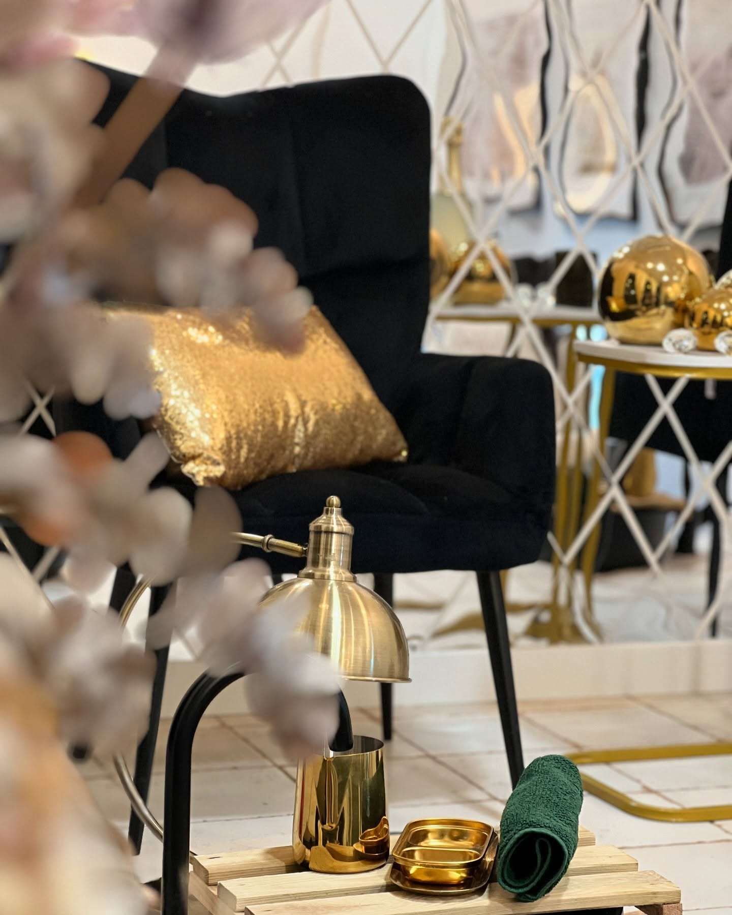 Sillón negro con cojín dorado, lámpara y decoración sobre un palé. Espejo y mesa auxiliar al fondo.