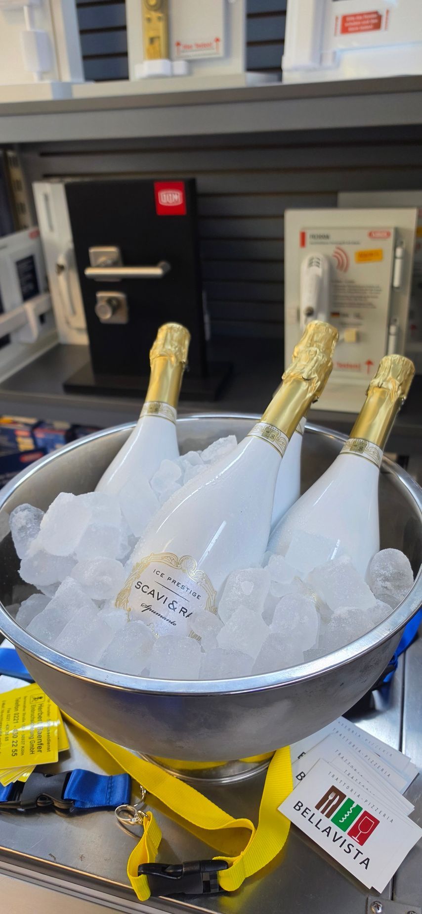 Drei Champagnerflaschen kühlen in einem Eisbehälter auf einem hellen Ladendisplay.
