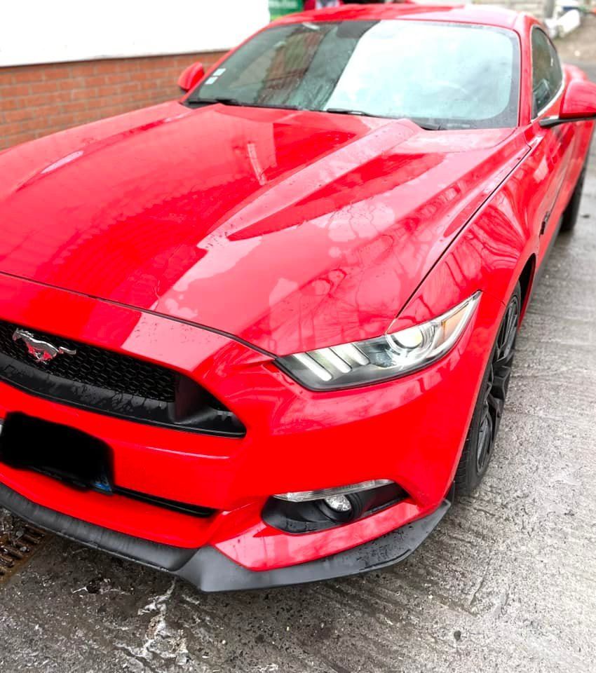 Voiture rouge garée sur une chaussée mouillée.