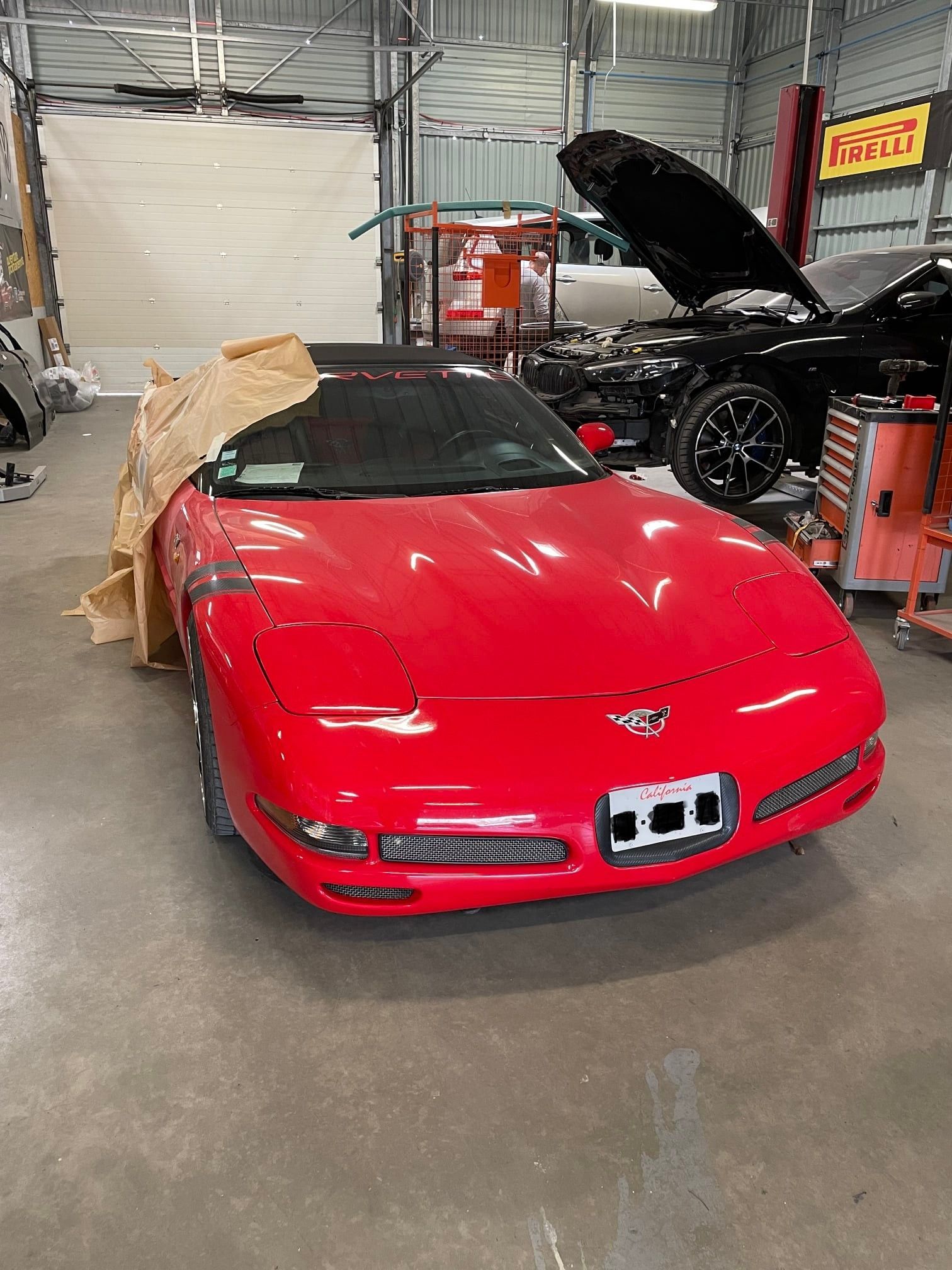 Voiture rouge dans un atelier de réparation, recouverte de papier brun.