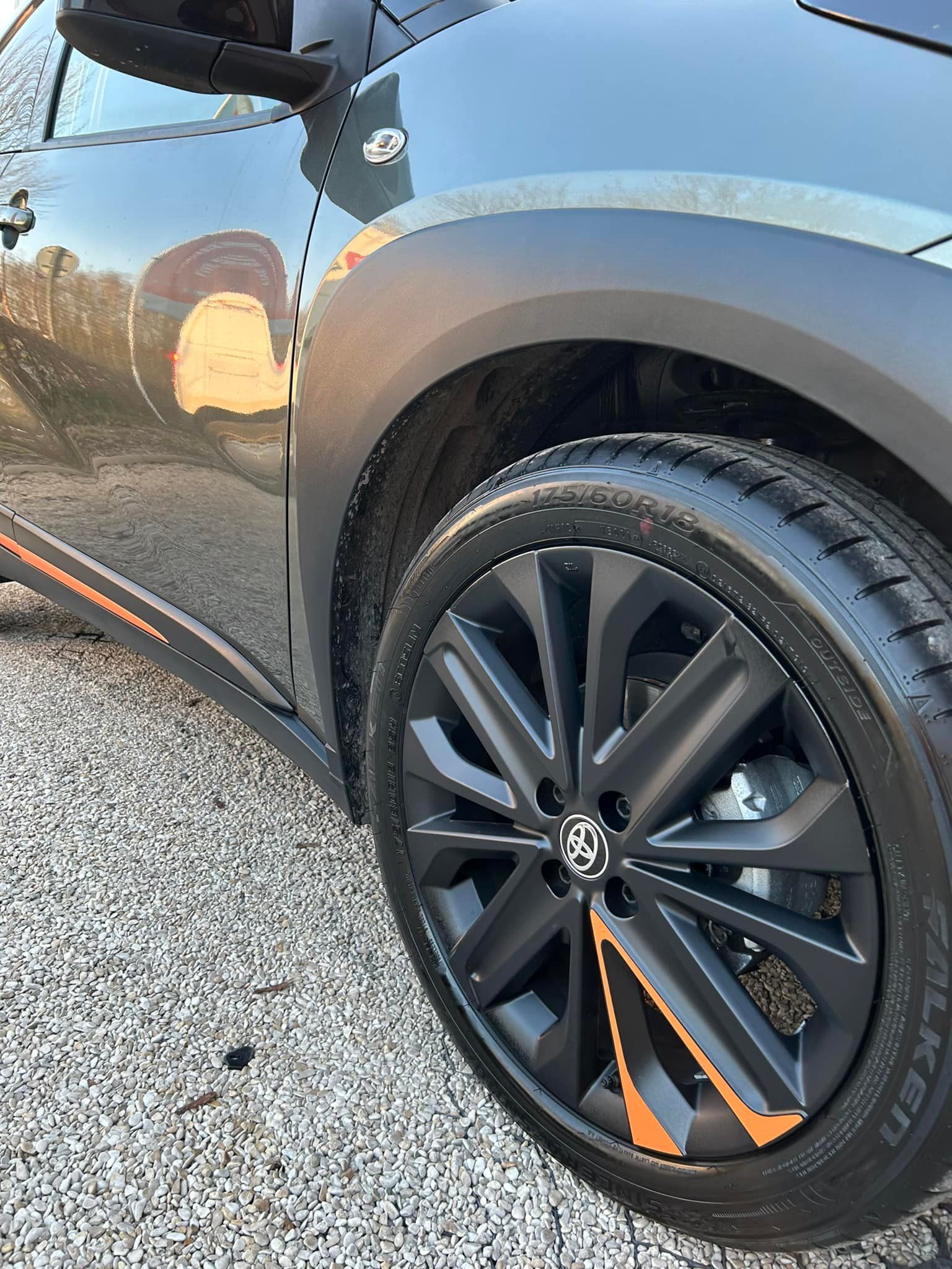Roue de voiture noire avec des accents orange, gros plan.