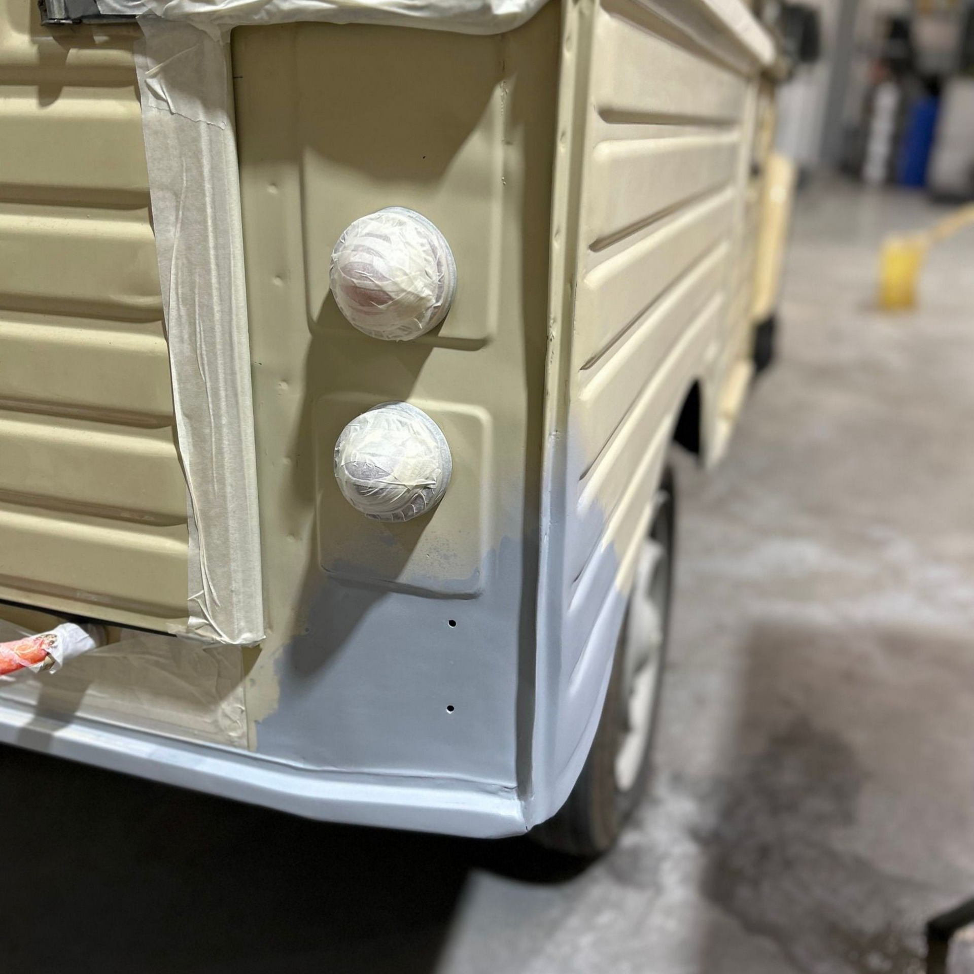 Coin arrière du véhicule beige avec deux feux masqués ; la partie inférieure est apprêtée.