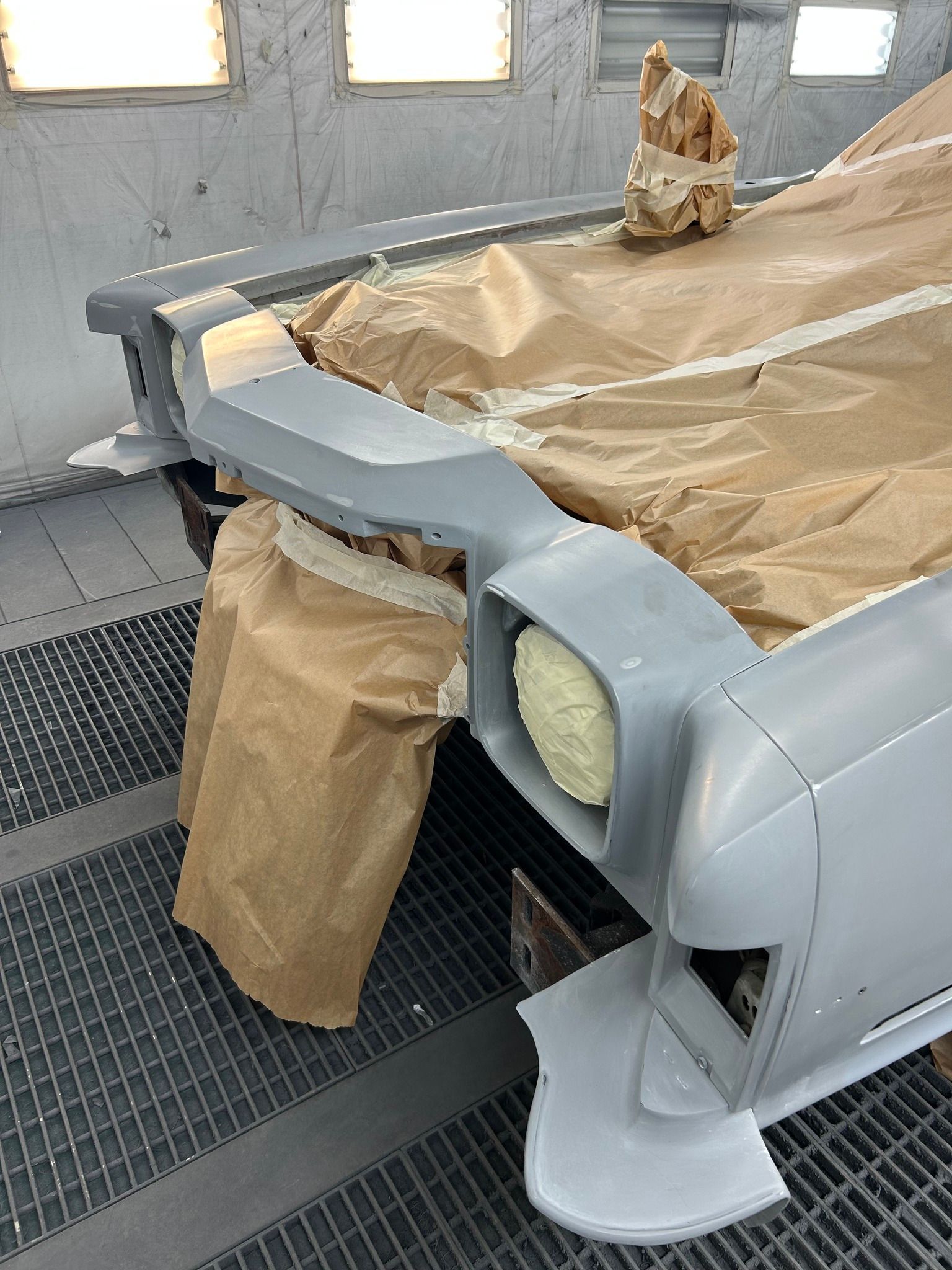 Pare-chocs de voiture masqué pour peinture en cabine de peinture ; apprêt gris, revêtement papier brun.