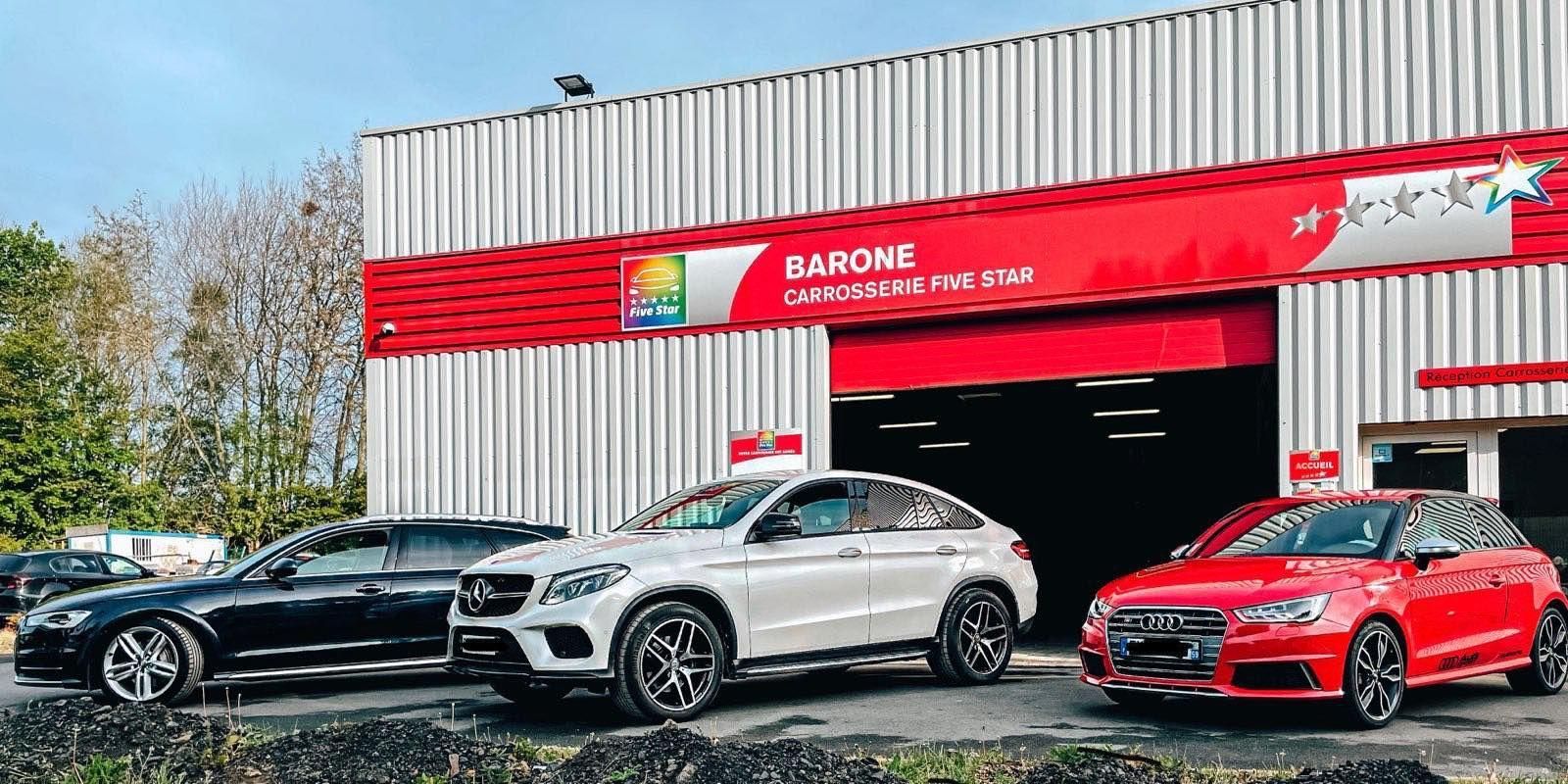 Voitures garées devant un bâtiment rouge et blanc, peut-être un garage ou un centre de service.
