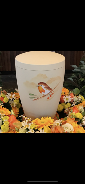 Urne mit einem gemalten Rotkehlchen auf einem Ast, umgeben von einem Blumenkranz.