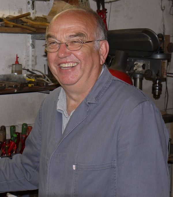 Ein Mann mit Brille lächelt vor einer Bohrmaschine