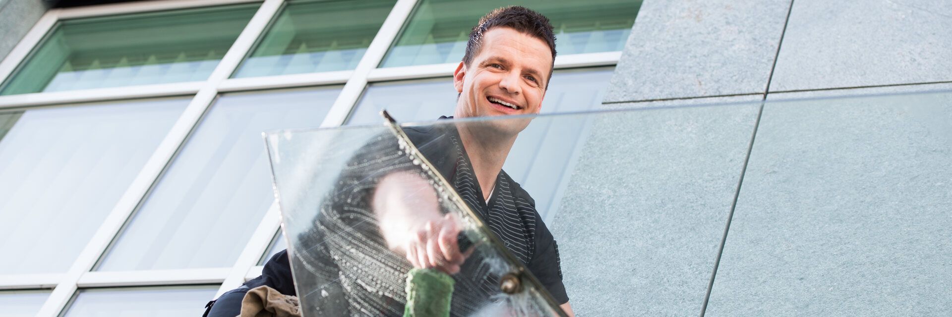 Ein Mann putzt ein Fenster an der Seite eines Gebäudes.