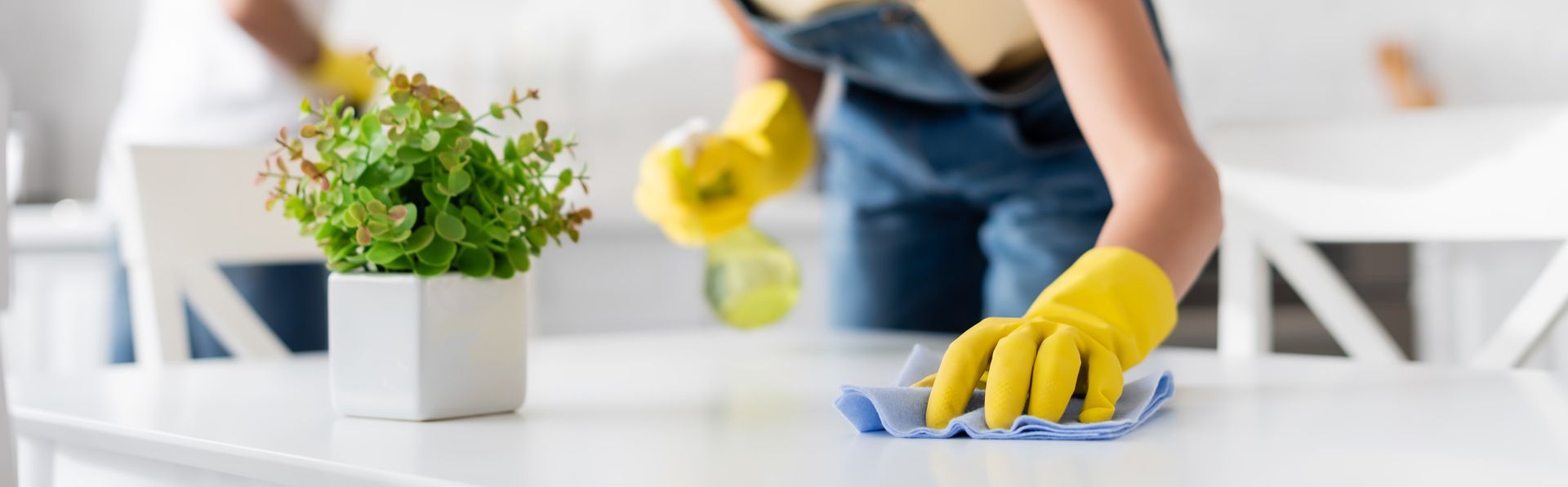 Eine Person mit gelben Handschuhen reinigt eine Theke mit einem Tuch.