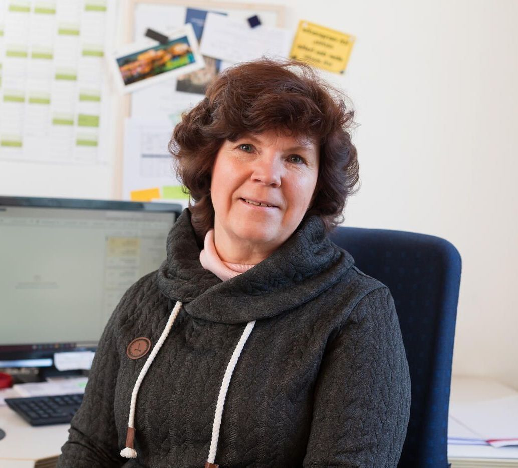 Eine Frau in einem schwarzen Pullover sitzt vor einem Computer