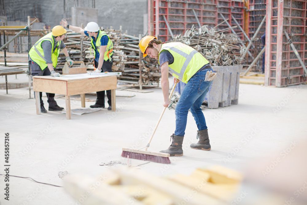Trois ouvriers en tenue de sécurité et casques de chantier sur un chantier de construction.