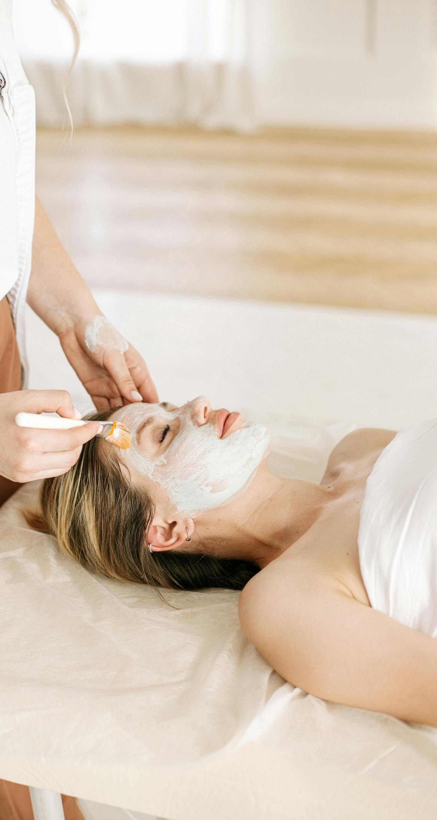 Une personne recevant un soin du visage doux avec un masque, les yeux fermés, dans un cadre relaxant.