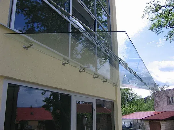 Una marquesina de cristal, montada sobre una estructura de acero, situada sobre la entrada de un edificio
