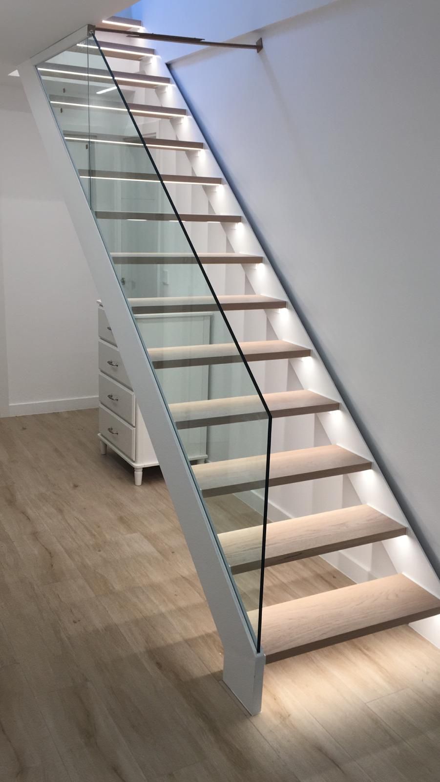 Escalera moderna con peldaños de madera, barandilla de cristal e iluminación LED integrada