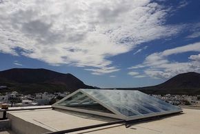 Un tragaluz en el tejado de un edificio con montañas al fondo.