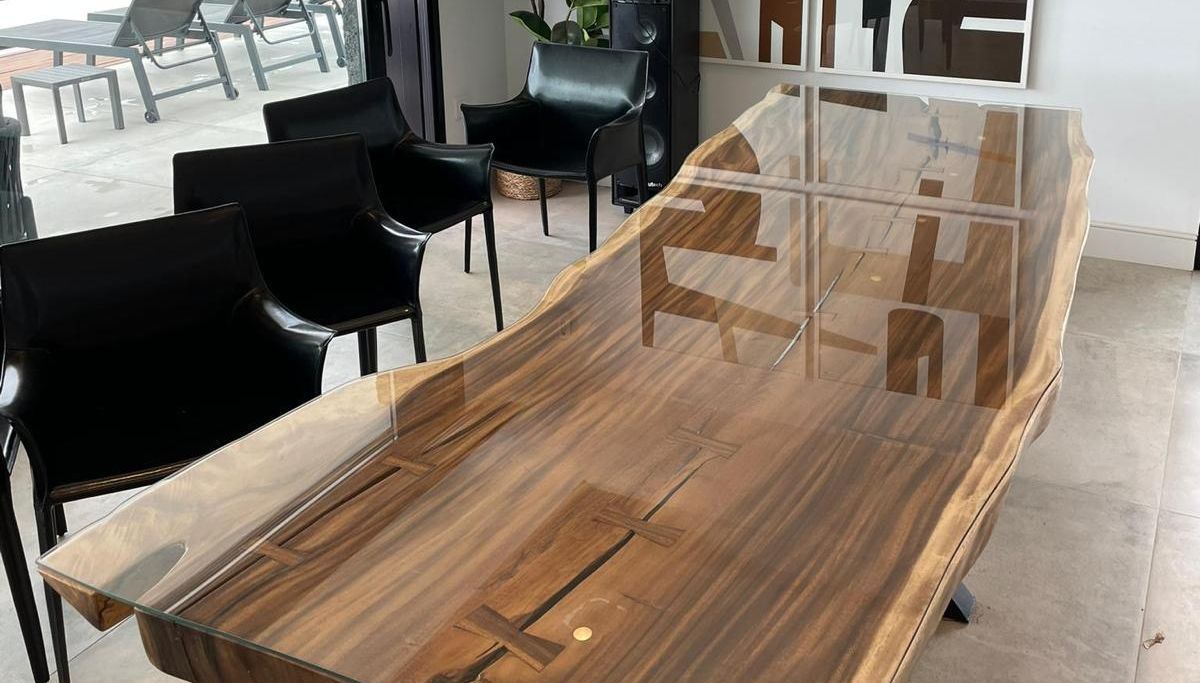 Una mesa de madera con tapa de cristal en una habitación con sillas.