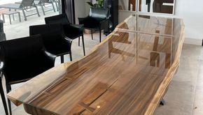 Una mesa de madera con tapa de cristal en una habitación con sillas.