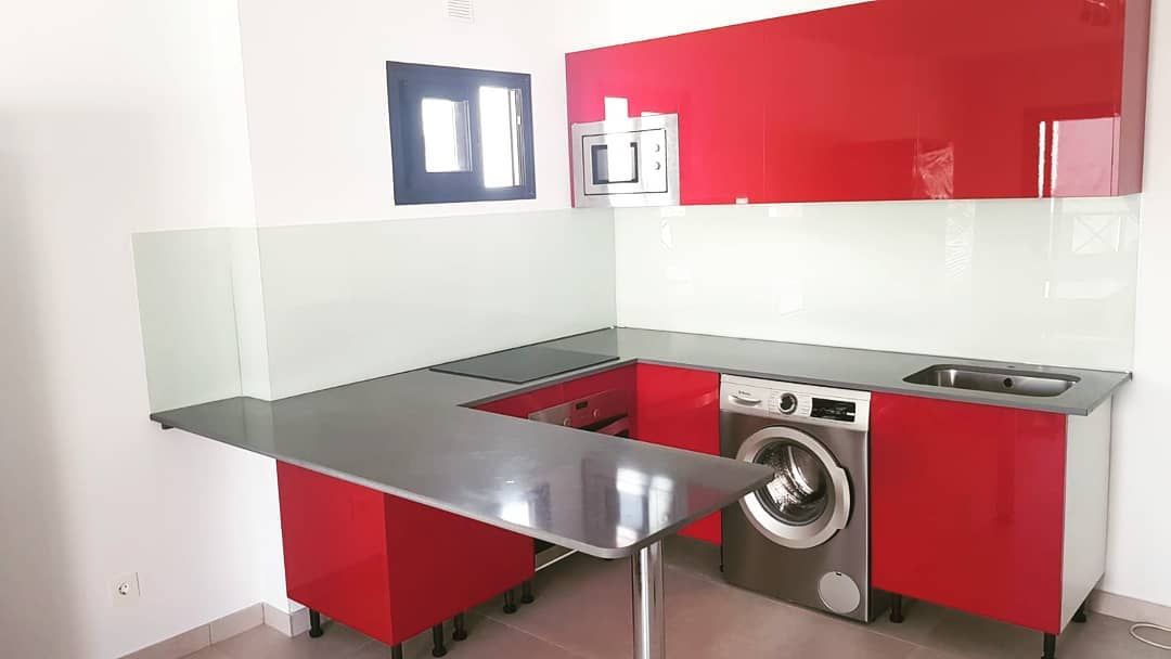 Una cocina con armarios rojos y lavadora.